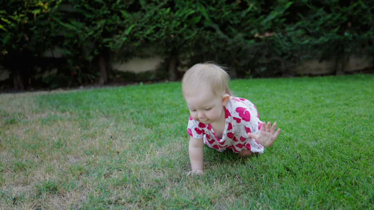 Bambino felice che gattona e gioca sull'erba verde in giardino