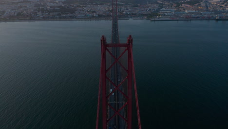 Aerial-view-of-the-traffic-across-Ponte-25-de-Abril-red-bridge-in-evening-light-in-Lisbon,-Portugal