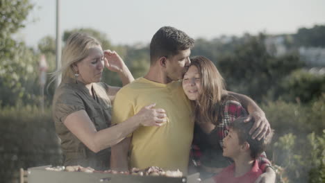 happy man embracing and kissing his children at barbecue grill