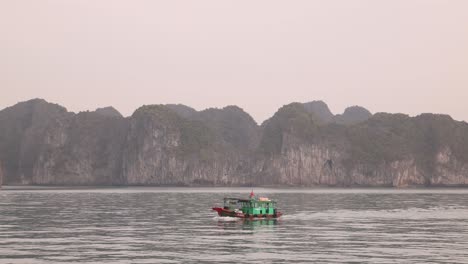 fishing-boat-floating-by-jagged-cliffs-in-Cat-Ba-and-Halong-Bay-in-Northern-Vietnam