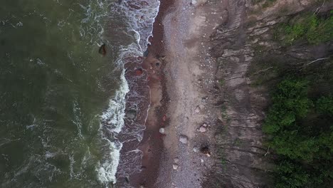 Desde-Una-Perspectiva-A-Vista-De-Pájaro,-El-Dron-Captura-Una-Foto-Desde-Arriba-De-La-Imponente-Costa-Del-Acantilado-A-Lo-Largo-Del-Mar-Báltico-De-Lituania,-Con-Grandes-Olas-Y-Los-Tonos-Cambiantes-Del-Agua-Verde.