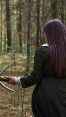 woman in long dress walks in forest with crossbow in hands, historical reconstruction, role playing games