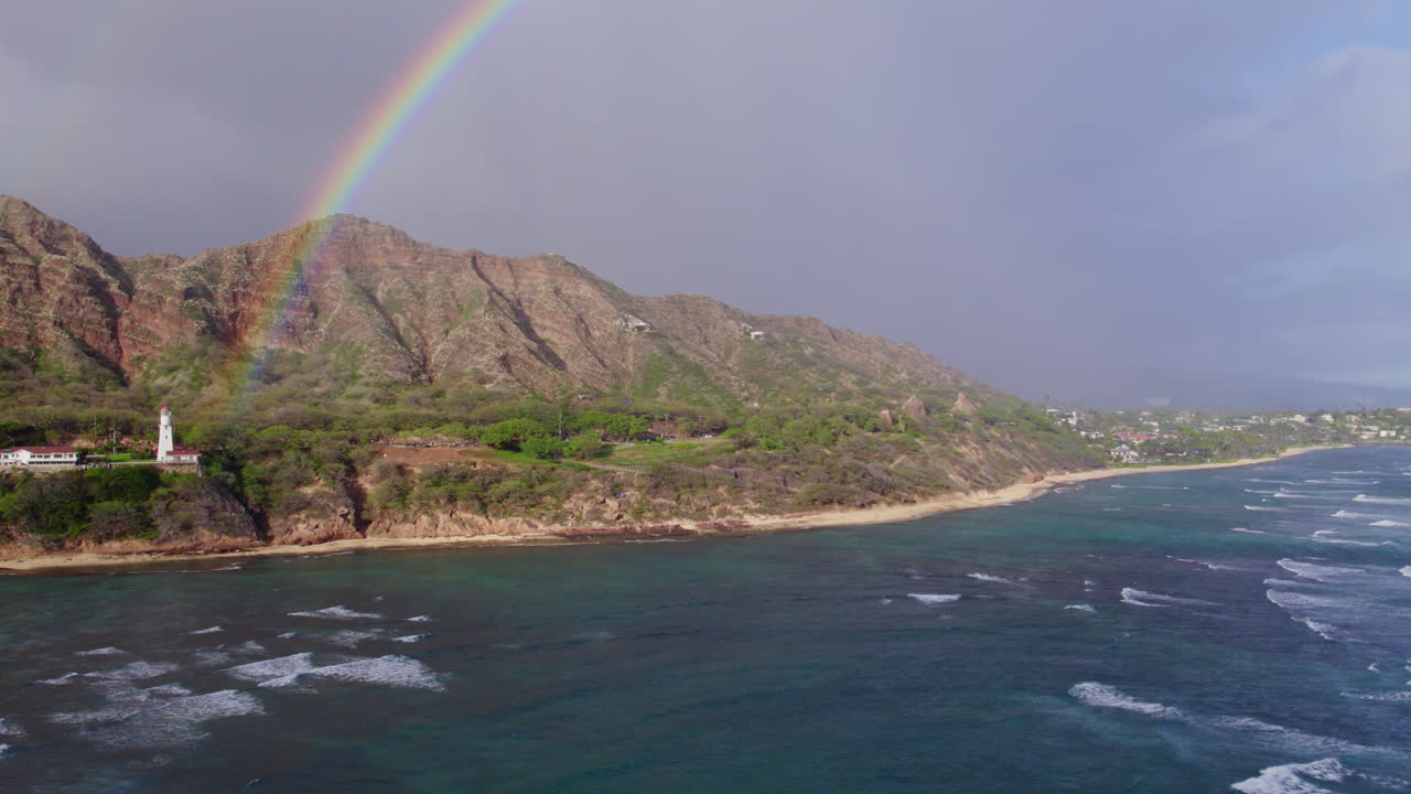imágenes de drones perfectamente atrapando un arco iris contra las montañas volcánicas en el faro de diamond head en la isla de oahu cerca de honolulu con las hermosas aguas azules del océano pacífico