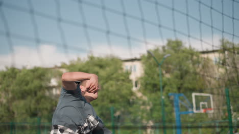 man leaps high attempting to slam volleyball back over net during intense training session, background features various sports facilities, emphasizing athleticism, action, and competition