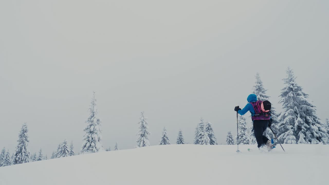 Donna che pratica sci alpinismo in un paesaggio invernale innevato della Slovacchia, in slow motion.