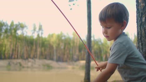 un niño de 3-4 años aprende a montar una tienda en el bosque a la orilla del lago. retrato de un niño durante un viaje al bosque con su padre