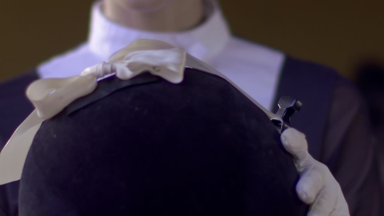 우아 한 승마 여성 이 헬 ⁇  을 착용 하고 승마 를 준비 하고 있는 모습 을 느리게 찍고 있다