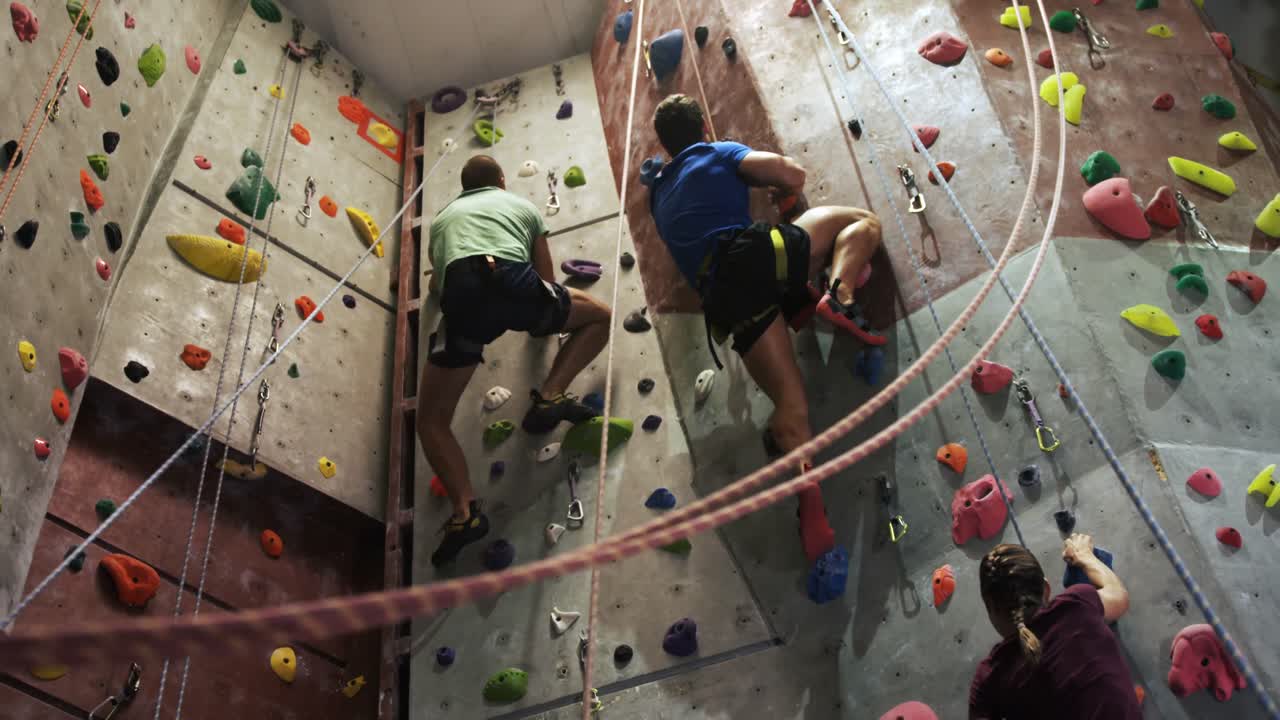 hombres y mujeres escalando una pared artificial en el gimnasio de bouldering 4k