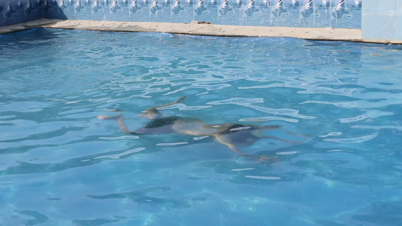 joven aislado bajo el agua nadando en una piscina con agua clara por la mañana