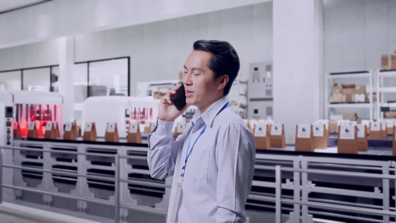 Side View Asian Male Professional Worker Standing With Conveyor for Packaging Coffee Beans in Bags at Coffee Factory, He Pick The Phone Up And Started To Specking To It With A Slicely Smile