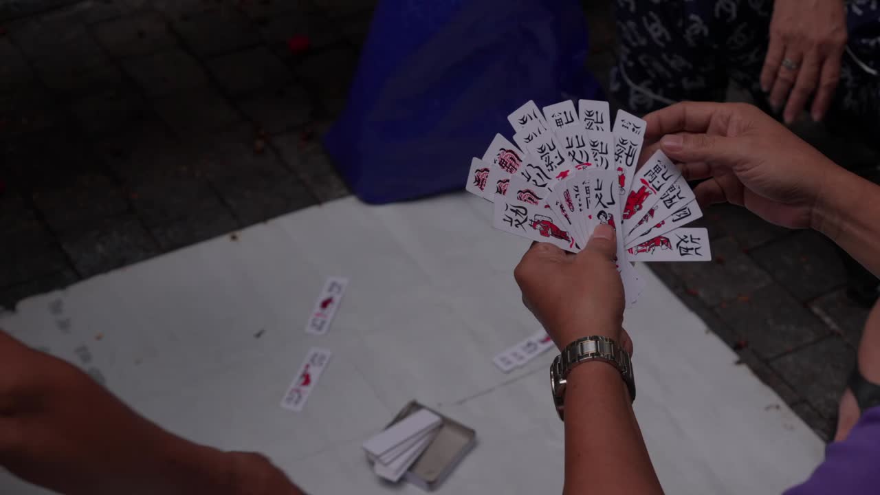 Persone che giocano al classico gioco di carte Tam Cuc sul marciapiede, al rallentatore