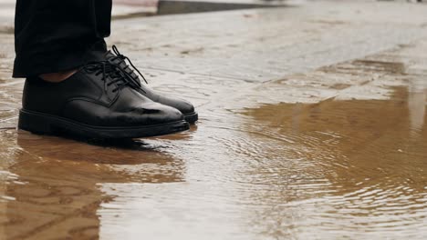 Business man tourist person with umbrella and raincoat on rainy european city street, lights reflecting, walking in Barcelona or Amsterdam during the rain