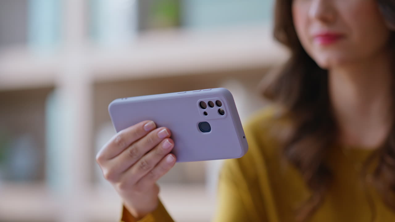Girl holding horizontal cellphone watching video closeup. Smiling woman playing