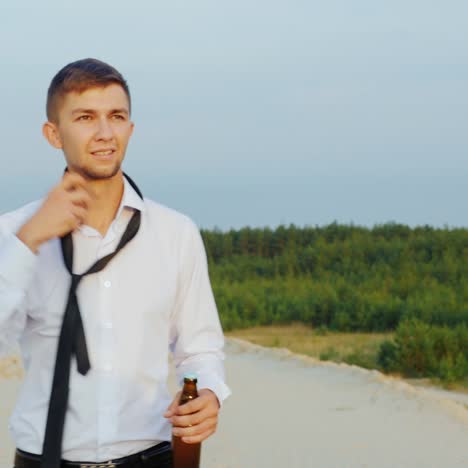 A-businessman-with-a-bottle-of-alcohol-walks-forward-on-the-sand-2