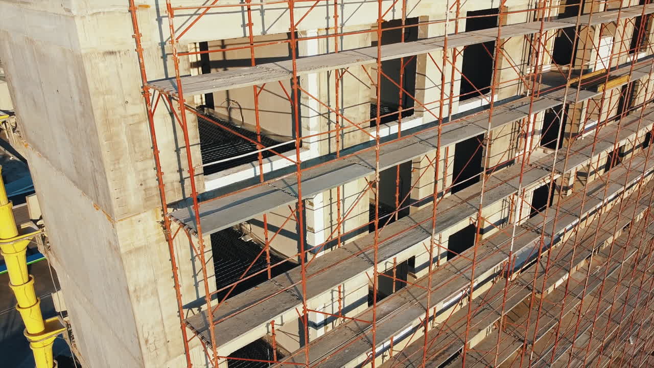 Construction works of a building with scaffolding on the facade. View from the drone. Bucharest, Romania
