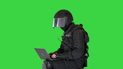 oficial de policía antidisturbios sentado y usando una computadora portátil en una pantalla verde, clave de croma