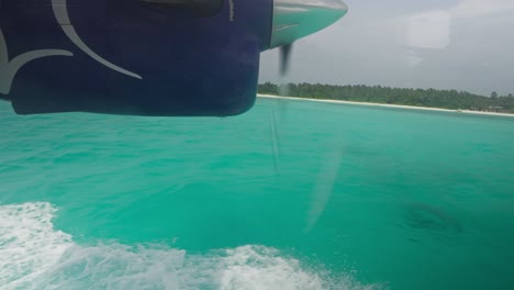 window view of seaplane landing in tropical azure water with engine propeller