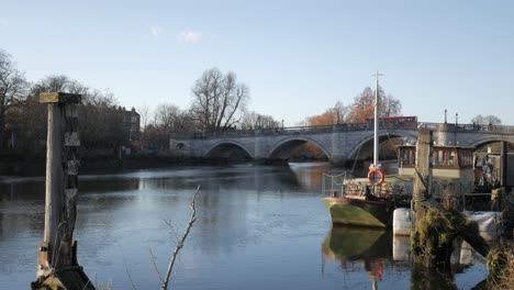 A scenic bridge over a calm river with boats nearby, evoking tranquility and history