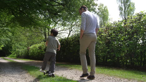 father and son ride scooter on countryside path shot on r3d