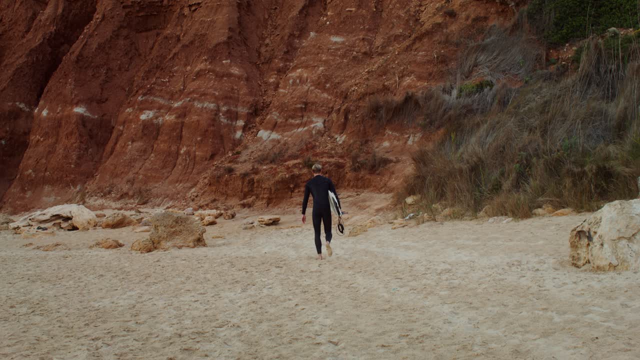 un surfista caminando por la playa con una tabla de surf