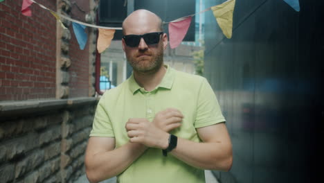 man in a lime green polo shirt posing in an alley