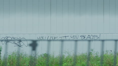 filming out of a train window during the early dawn passing graffiti on the wall of a building in sydney australia