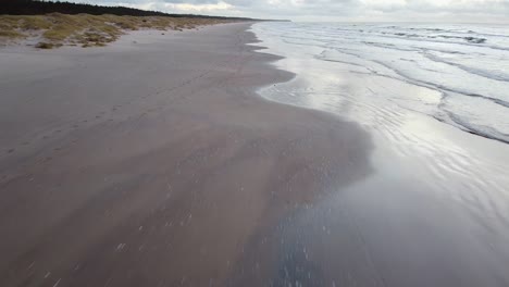 Aerial-drone-flyover-at-Perkone-sandy-beach-Baltic-sea-coastline-after-the-sunset,-no-people,-autumn,-spring,-relieving-shot