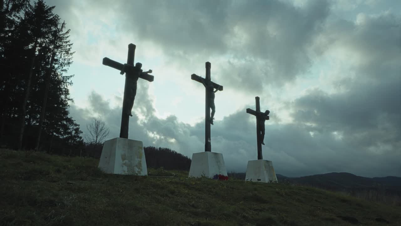 예수 그리스도의 십자가 처형을 나타내는 3개의 조각상 뒤로 흐르는 폭풍우 구름