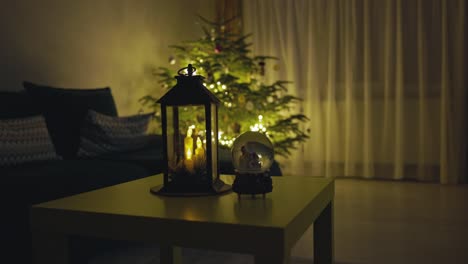 una linterna de vela y un globo de nieve colocados cerca del árbol de navidad brillante - toma estática