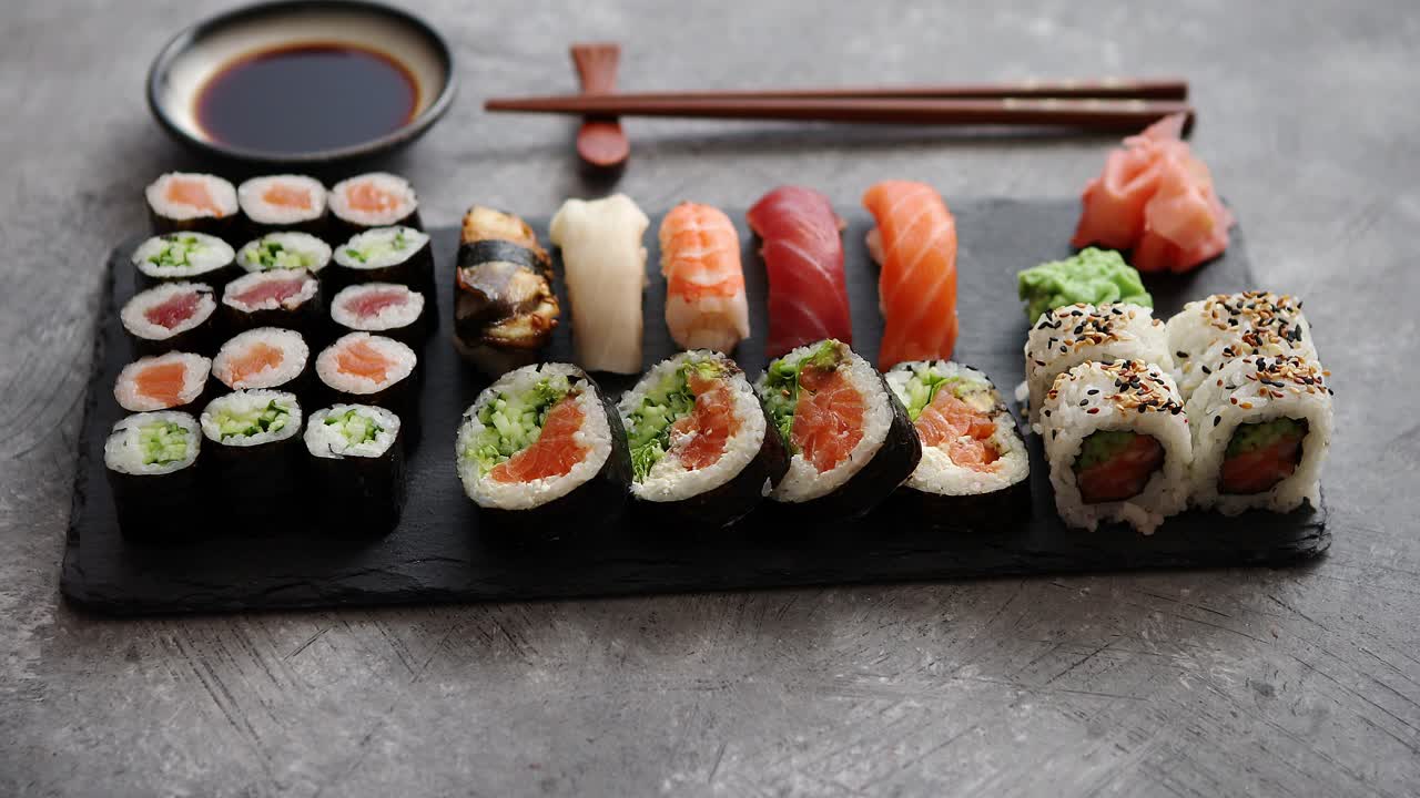 composición de diferentes tipos de rollos de sushi colocados en tablero de piedra negra