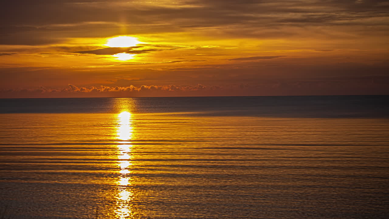 Picturesque Golden Sun Hiding Behind Clouds Over Sea Horizon With Reflections On Water Surface