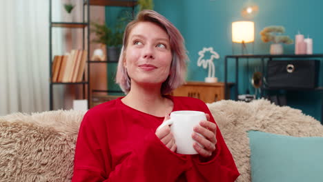 woman enjoying drinking coffee sits comfortably on couch relaxed satisfied calm leisure expression