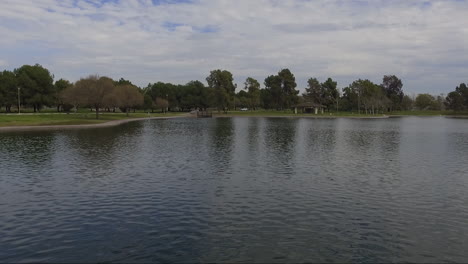 Flight-over-suburban-park-with-pond-and-ducks