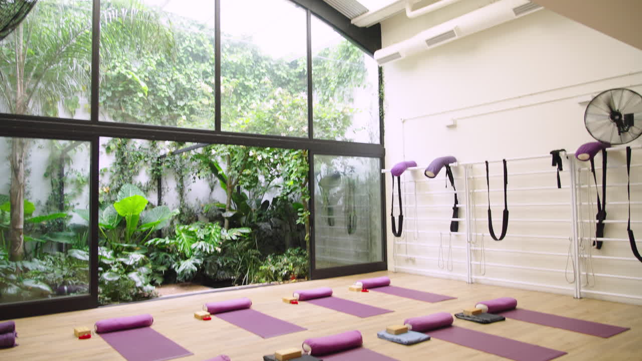 Tomt yogastudie med måtter og frodig haveudsigt