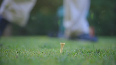 a tripod pan close up of a golf ball being driven by a male golfer