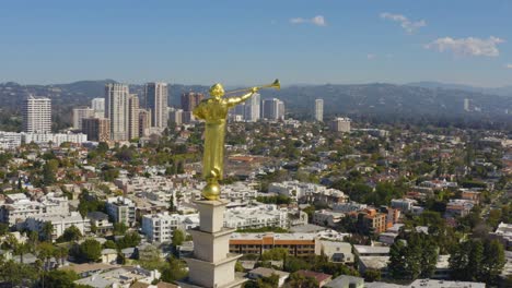 vuelo aéreo cinematográfico alrededor de la hermosa estatua de edificio dorado con edificios del centro de la ciudad