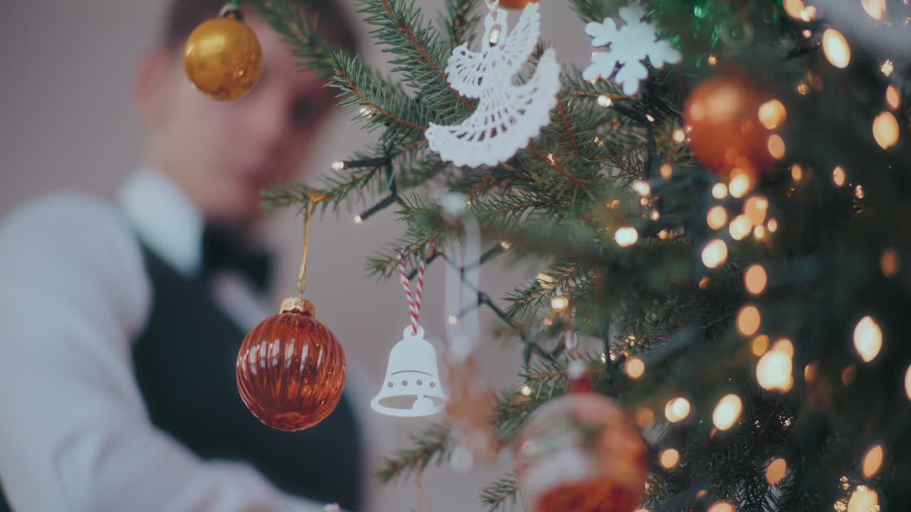 hombre colgando joyas rojas en el árbol de navidad decorado en casa