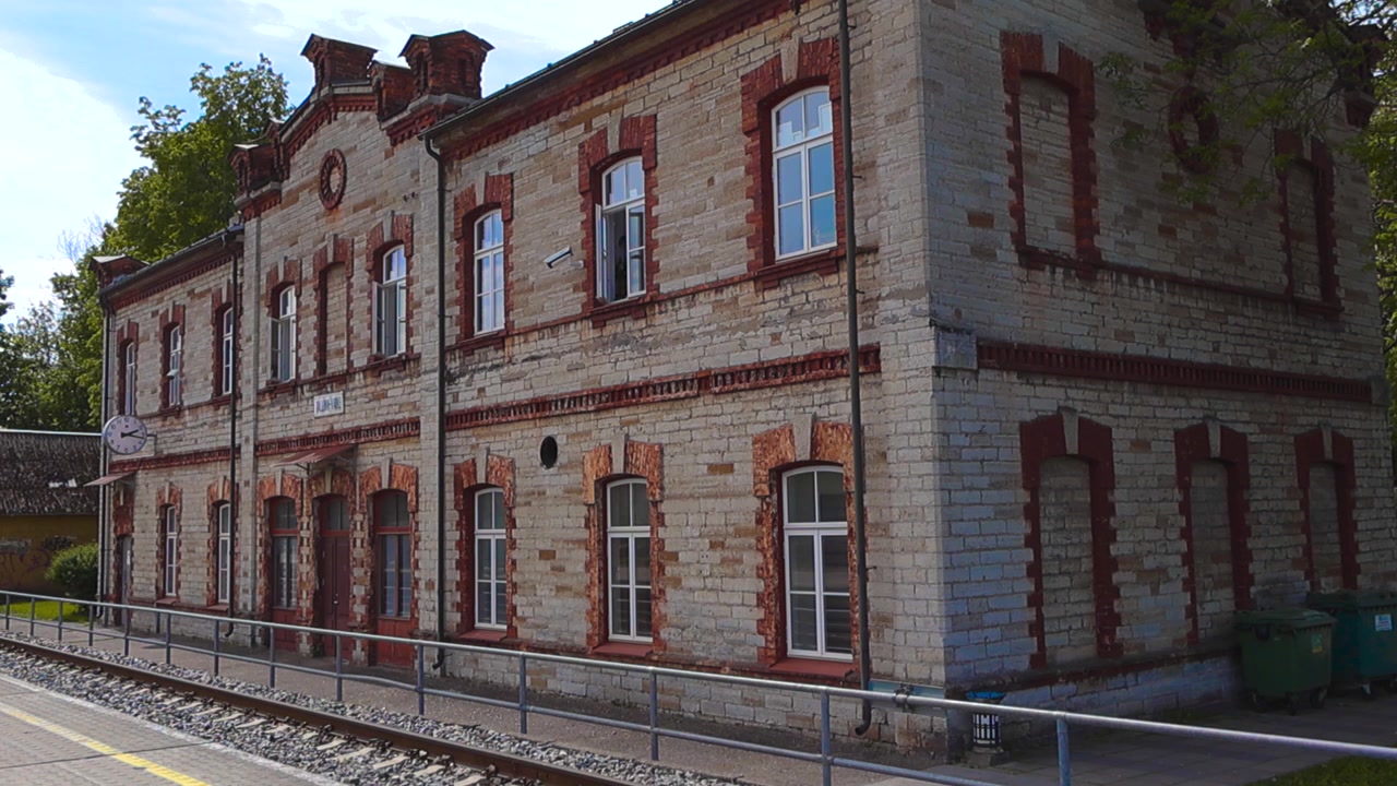 Architettura classica della stazione ferroviaria di Tallinn Vaike in Estonia, un edificio storico in mattoni con dettagli distintivi in mattoni rossi accanto ai binari vuoti in una soleggiata giornata estiva