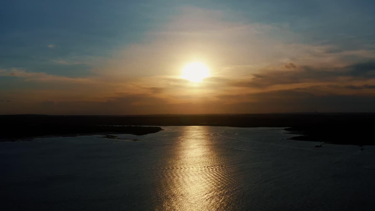 Stunning aerial drone static shot of a golden sunset reflecting onto the water of a large amazonian river in Joao Pessoa, Brazil