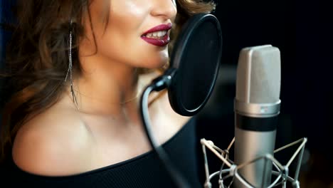 una chica joven cantando en un micrófono en un estudio.