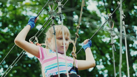 entertainment in summer camp - a child learns to use insurance cables climbs high in the branches of