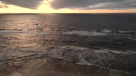 Toma-Aérea-De-La-Hermosa-Puesta-De-Sol-Sobre-Las-Olas-Del-Océano-En-La-Playa-De-Arena