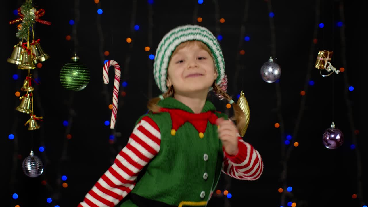 Dospívající dívka v kostýmu vánočního skřítka. Dělá vítězné gesto, říká „Ano“.