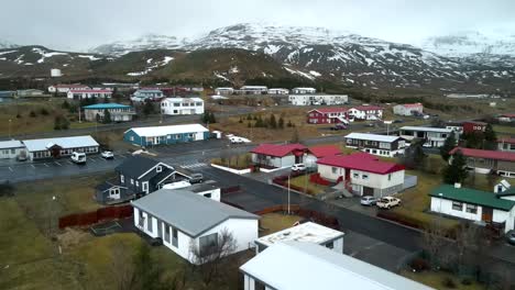 un avión no tripulado de 4k cinematográfico ofrece una vista aérea de casas multicolores anidadas bajo las montañas islandesas, presentando una perspectiva única y impresionante.