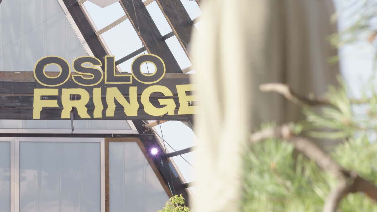 Pedestrians pass the Oslo Fringe entrance sign