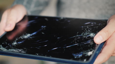 a man holds a tablet with a broken screen 2