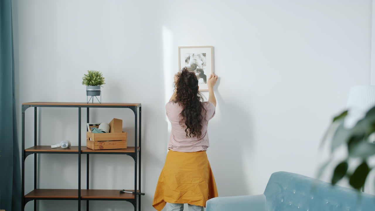 mujer colgando un cuadro en la pared