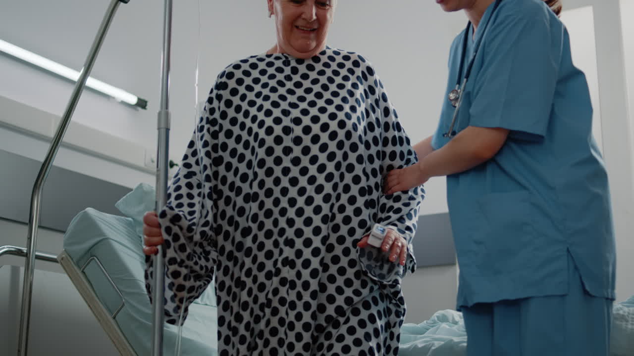 Medical assistant giving walking support to aged woman