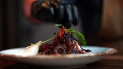 chef con guantes montando plato de pulpo con guarnición a cámara lenta