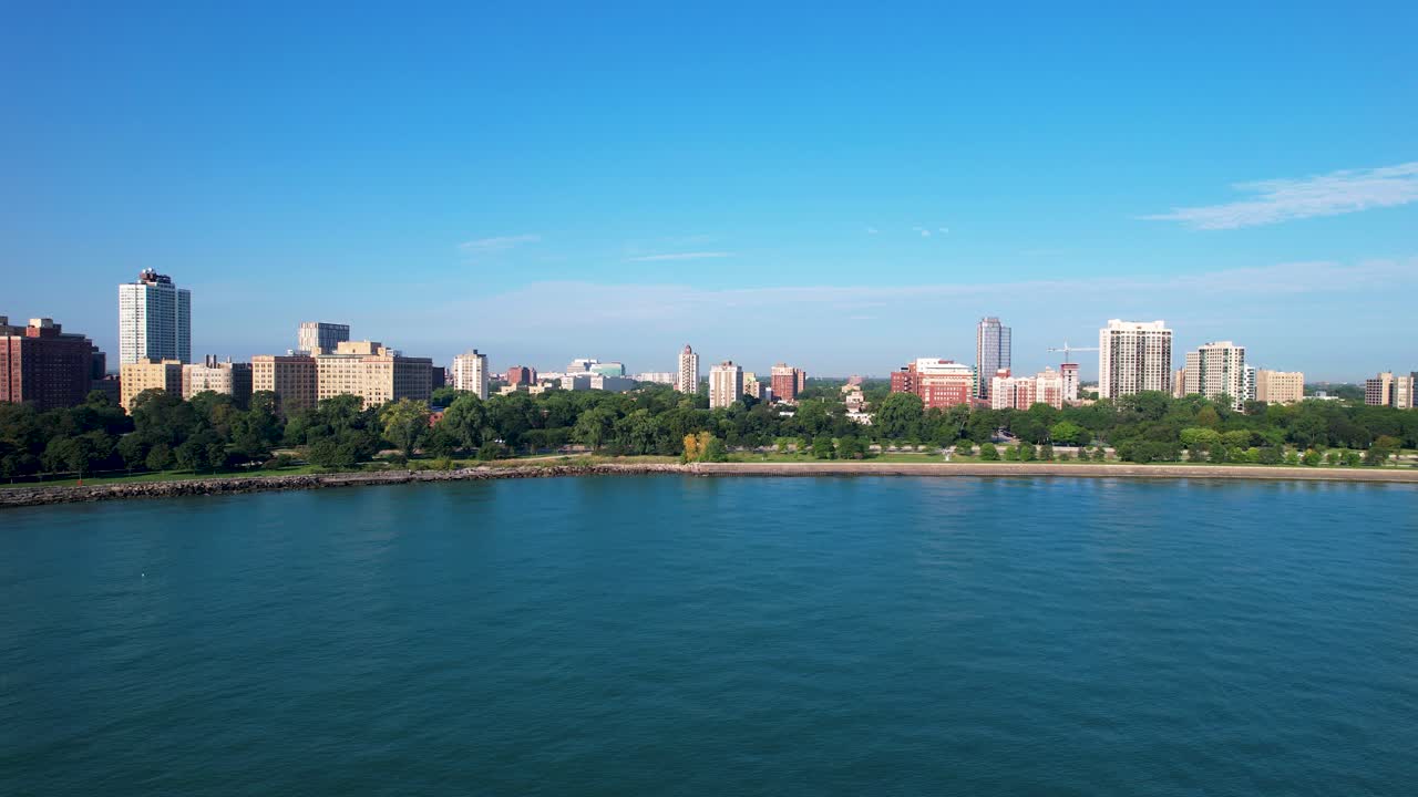푸른 물과 아파트 건물이 있는 울창한 초록색 나무가 있는 해안가 공원
